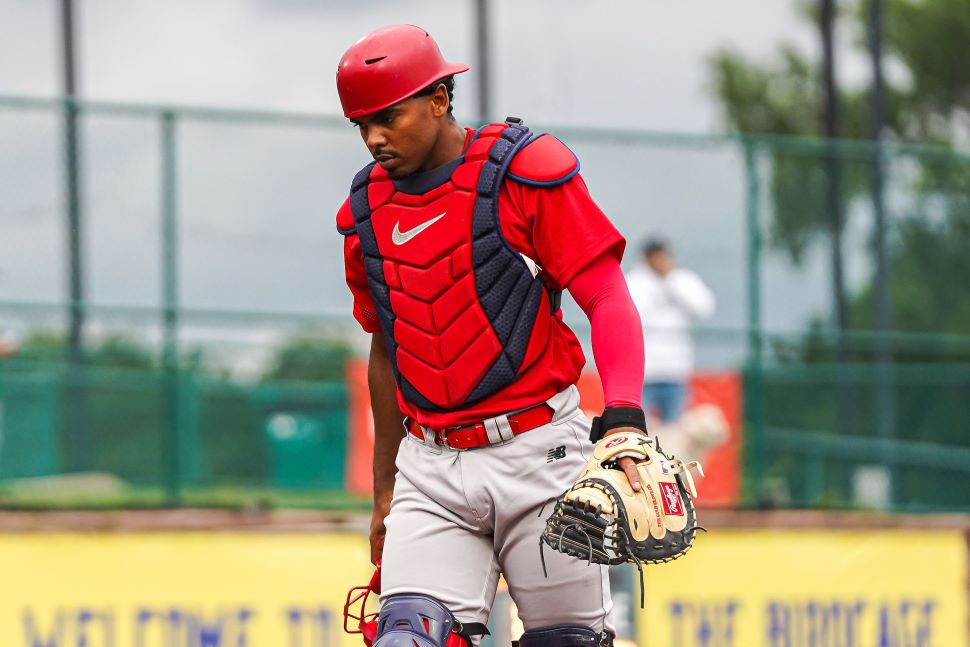 A catcher in gear walks with his head down