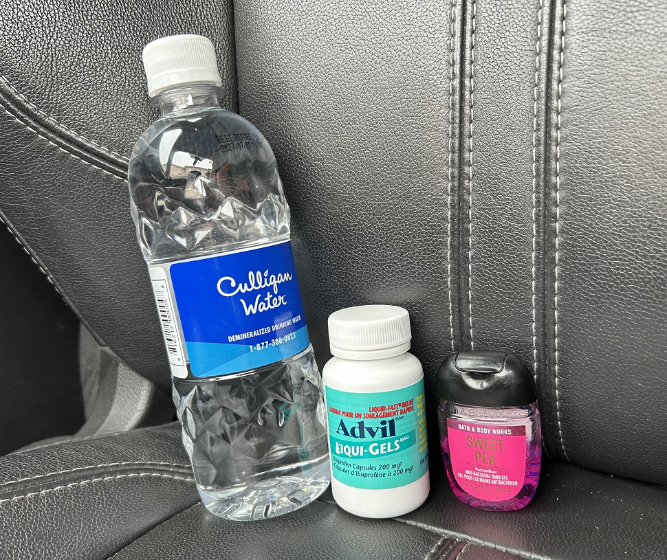 A bottle of Culligan Water with a blue label that reads "Culligan Water" and "DEMINERALIZED DRINKING WATER." A white bottle of Advil Liqui-Gels with a turquoise label that reads "Advil LIQUI-GELS" and "Liquid-Filled Capsules 200 mg Pain Reliever/Fever Reducer (NSAID) Ibuprofen 200 mg." A small container of Bath & Body Works hand sanitizer labeled "SWEET PEA" in pink, with additional text indicating it is an antibacterial hand gel containing essential oils.