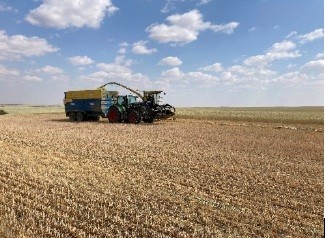 photo showing tractor and silage harvester with a grain truck in a field 