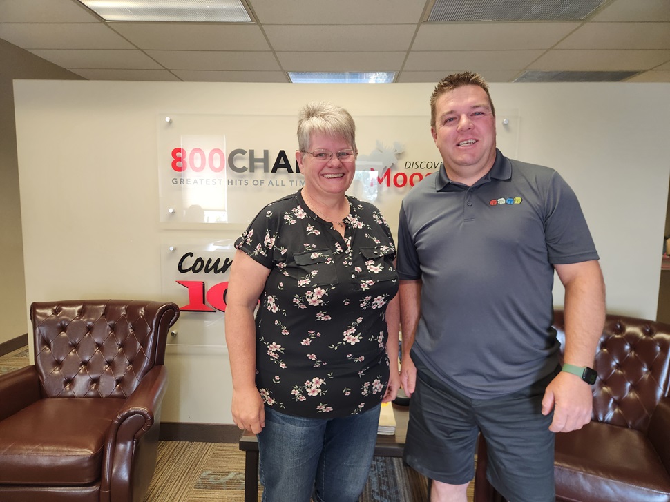 A man and Woman standing next to each other in front of the Golden West Moose Jaw logos.