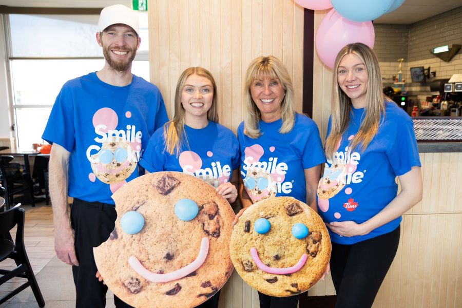 four people holding up giant smiley face cookies