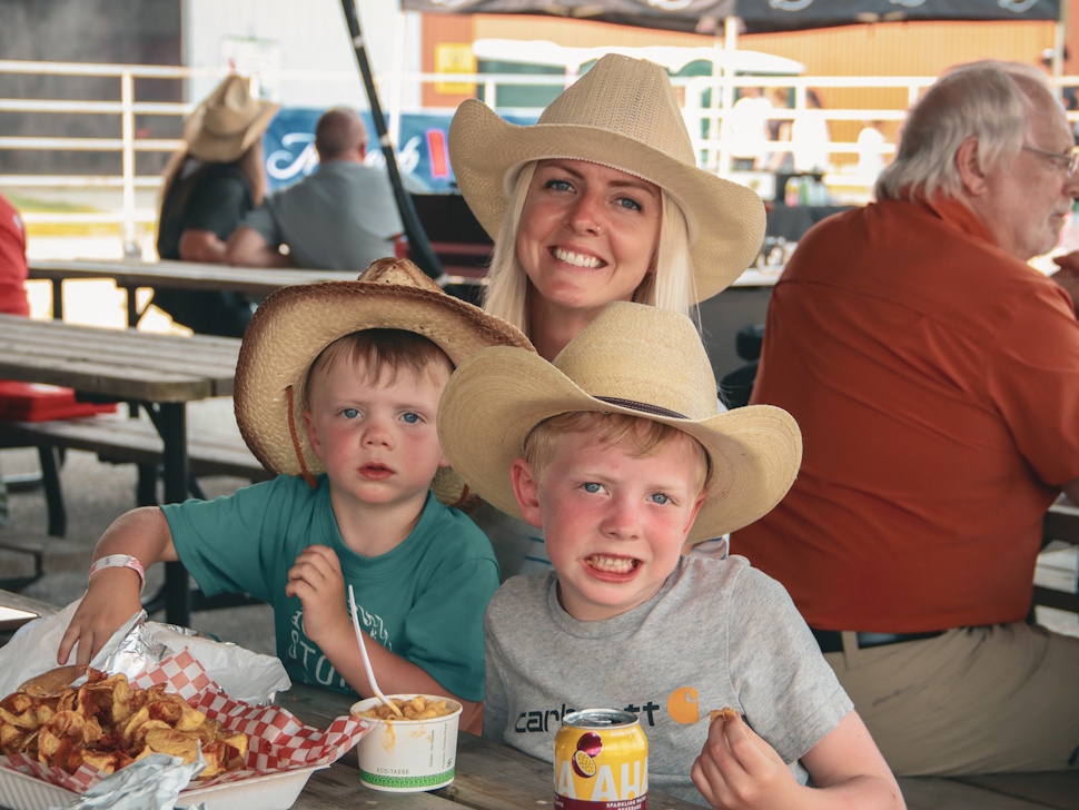 A mother and her children smile while enjoying food together at the Manitoba Stampede.