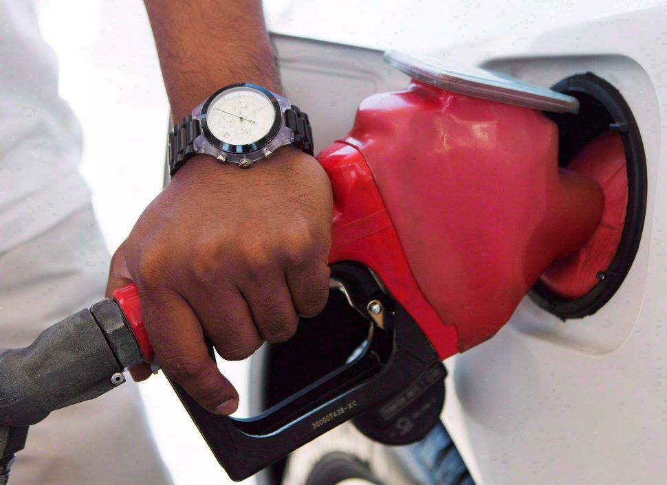 a close-up shows a hand on a gas pump, fuelling a vehicle