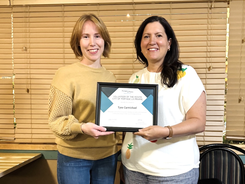 Tyne Carmichael stands with Mayor Sharilyn Knox, who presents her with the Volunteer of the Month award.