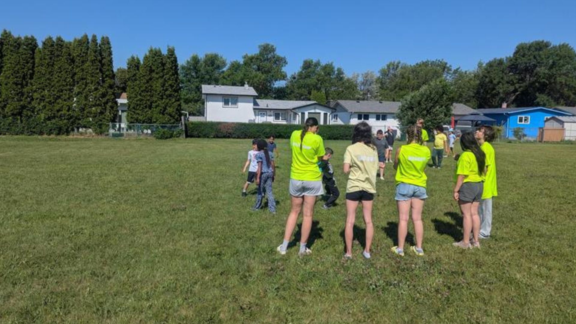 A group of 14 children on a field at a summer camp.