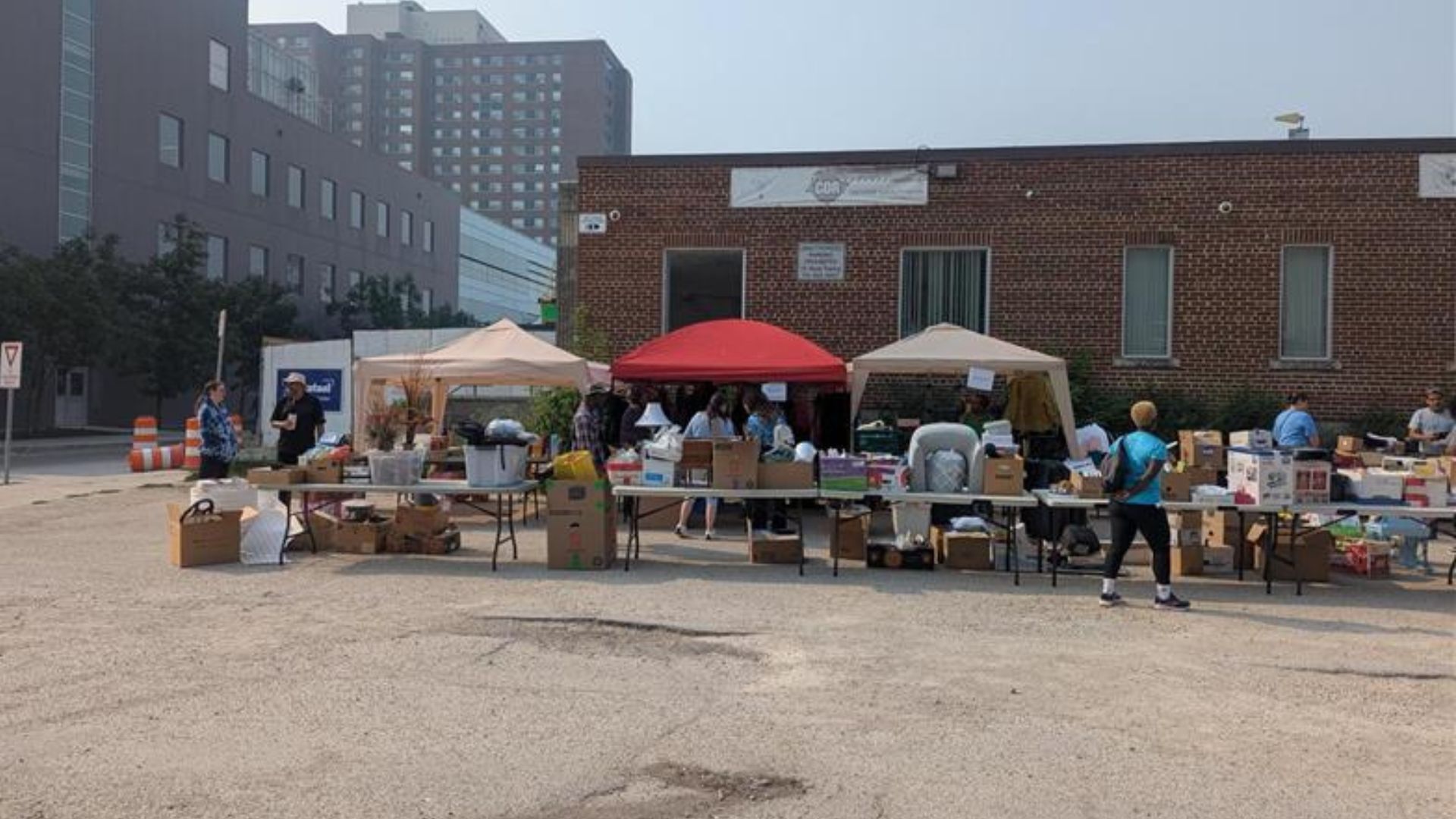 A yard sale in a parking lot with items spread out on tables and inside tents