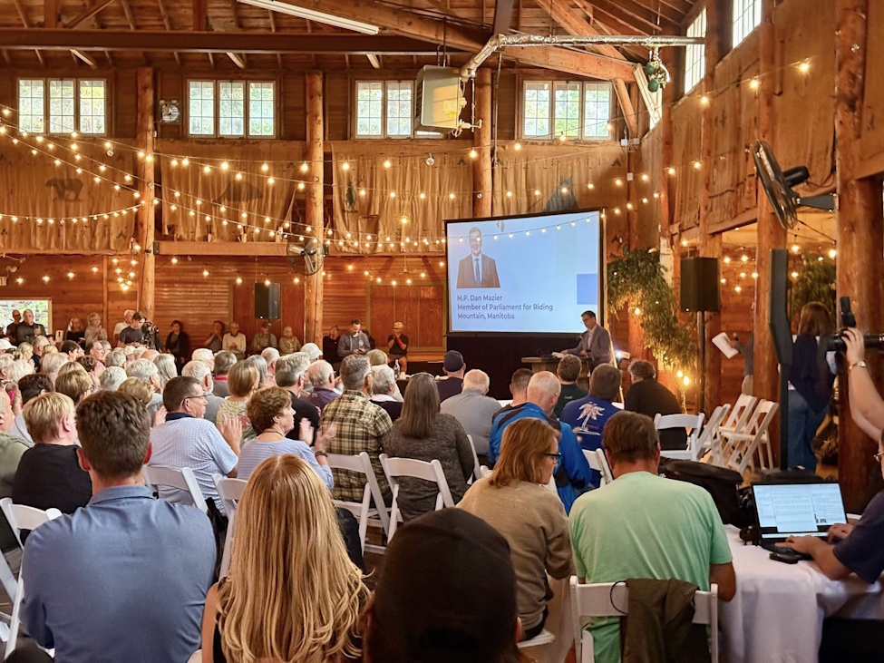a large group of people gathered in a large room listening to a speaker at a podium