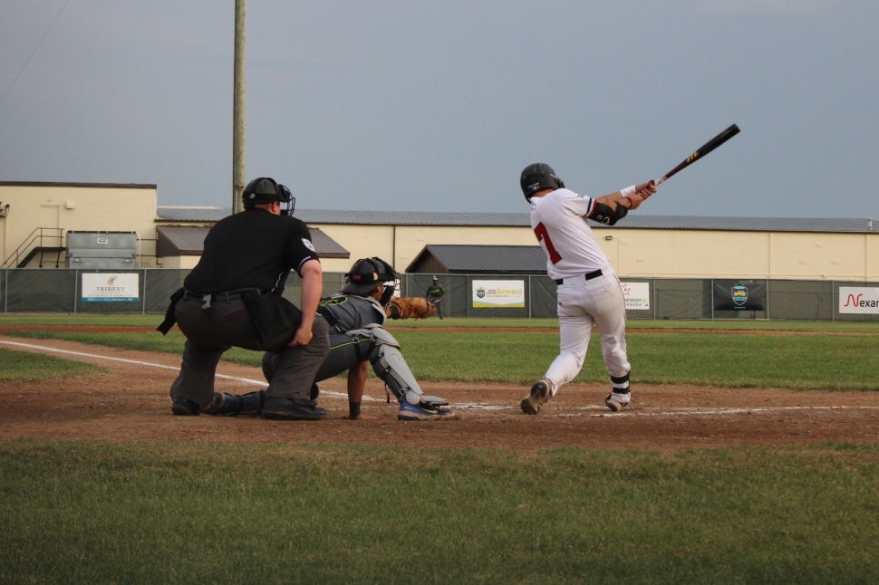 A baseball batter swinging with the umpire and back catcher in frame