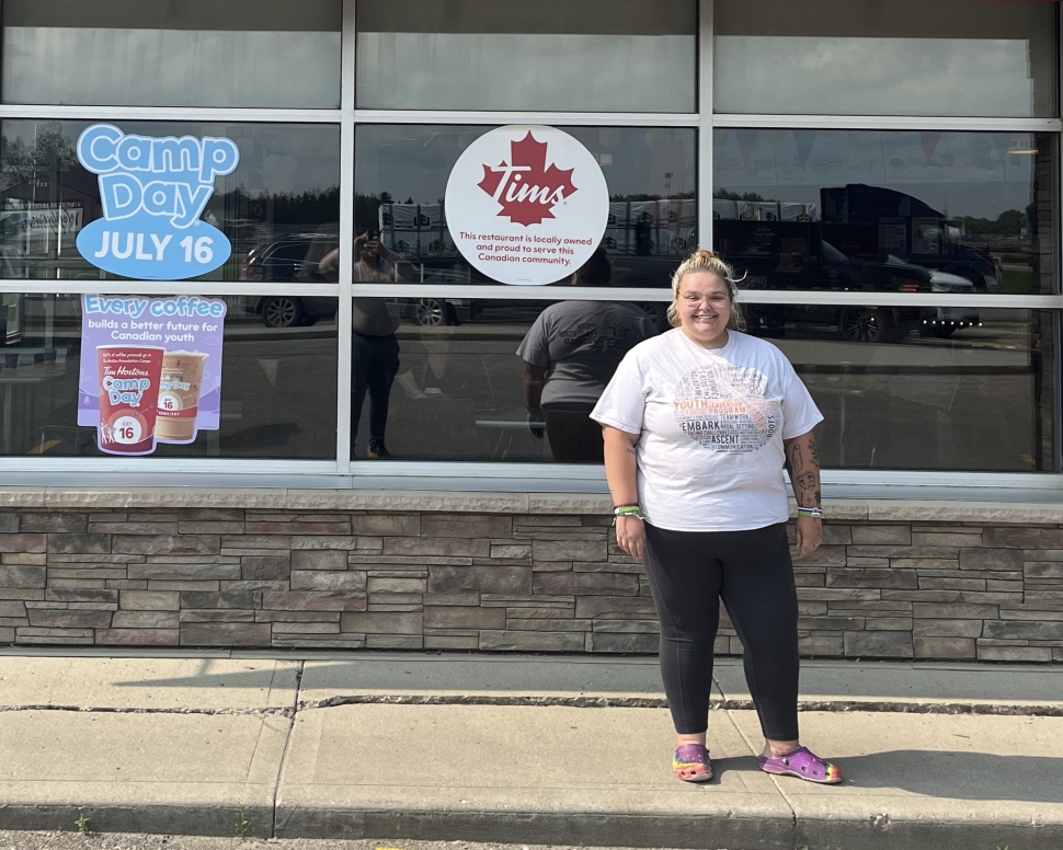 A woman in a white shirt and black pants standing in front of a business.