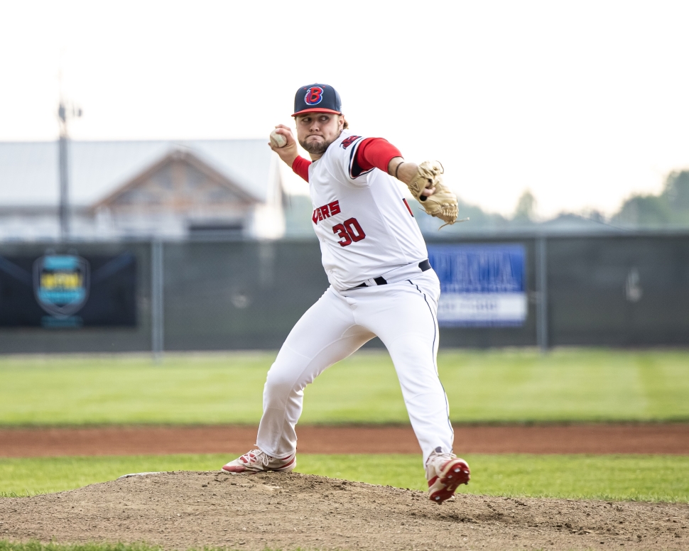 A baseball player in a white jersey pitching