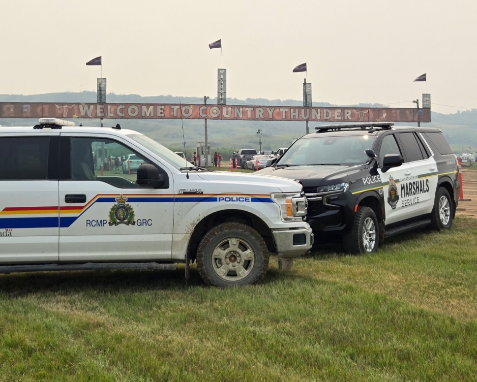 An RCMP vehicle and a Saskatchewan Marshal Service vehicle parked outside of the front gates of Country Thunder Saskatchewan
