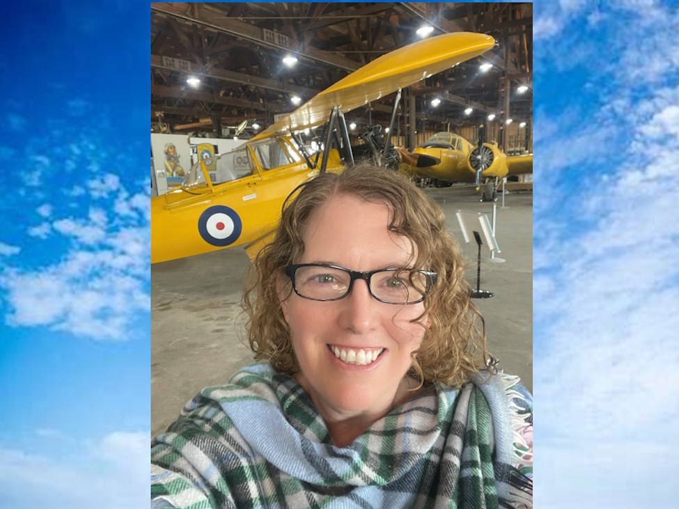 A young lady taking a photo selfie in front of a vintage airplane