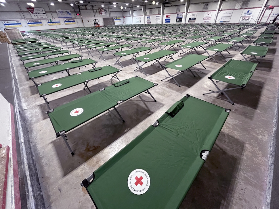 Rows of emergency cots lined up inside the Portage Curling Club, prepared for wildfire evacuees.