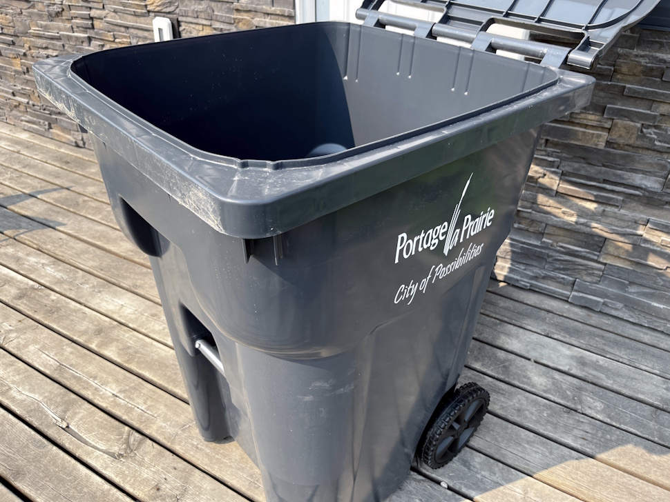 A new automated garbage cart with the lid open, placed near a residential curb.