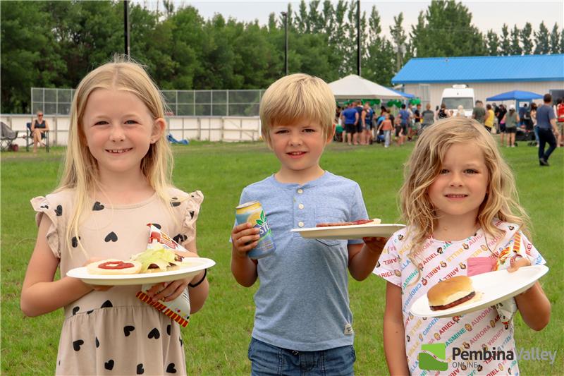 children stand with plates of food 