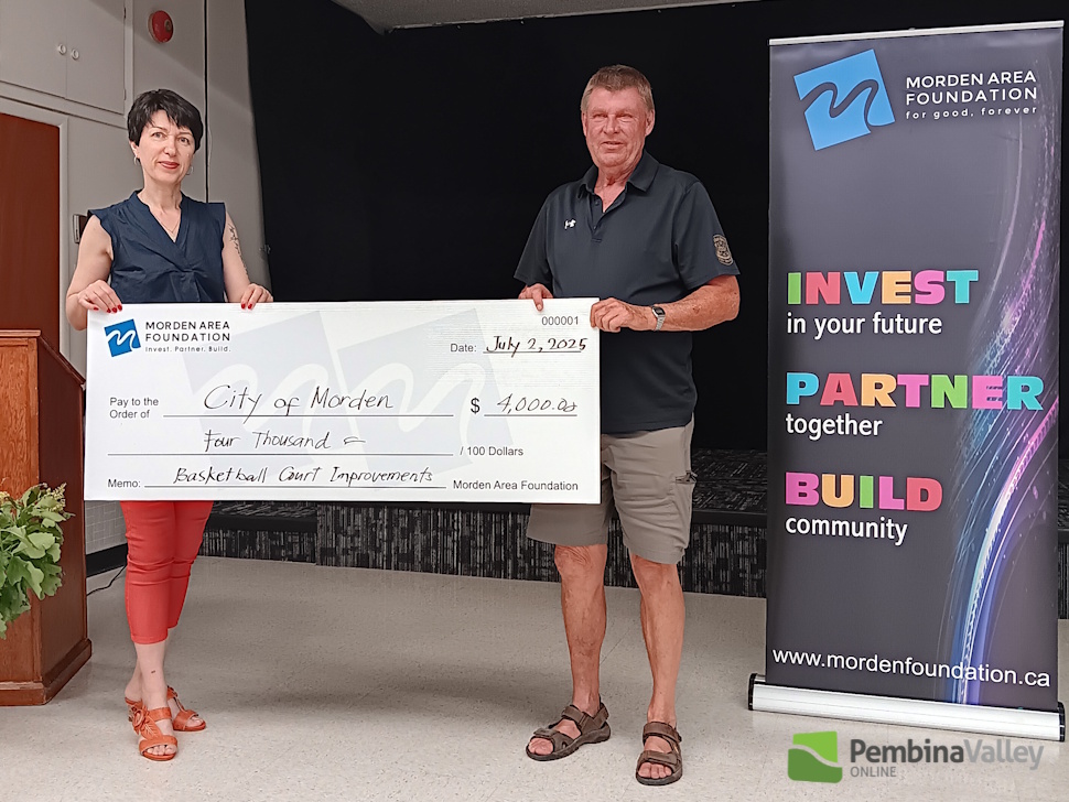 two people stand with a giant cheque between them 