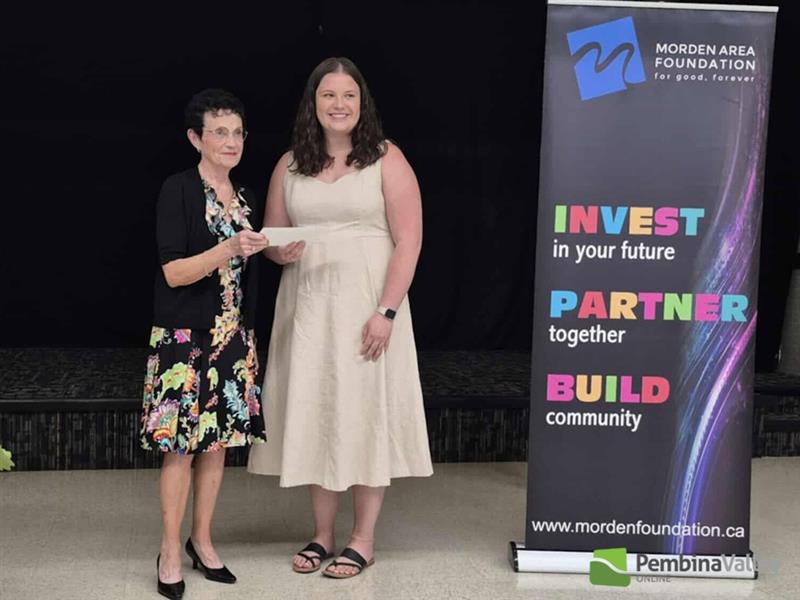 One woman presents a cheque to another 