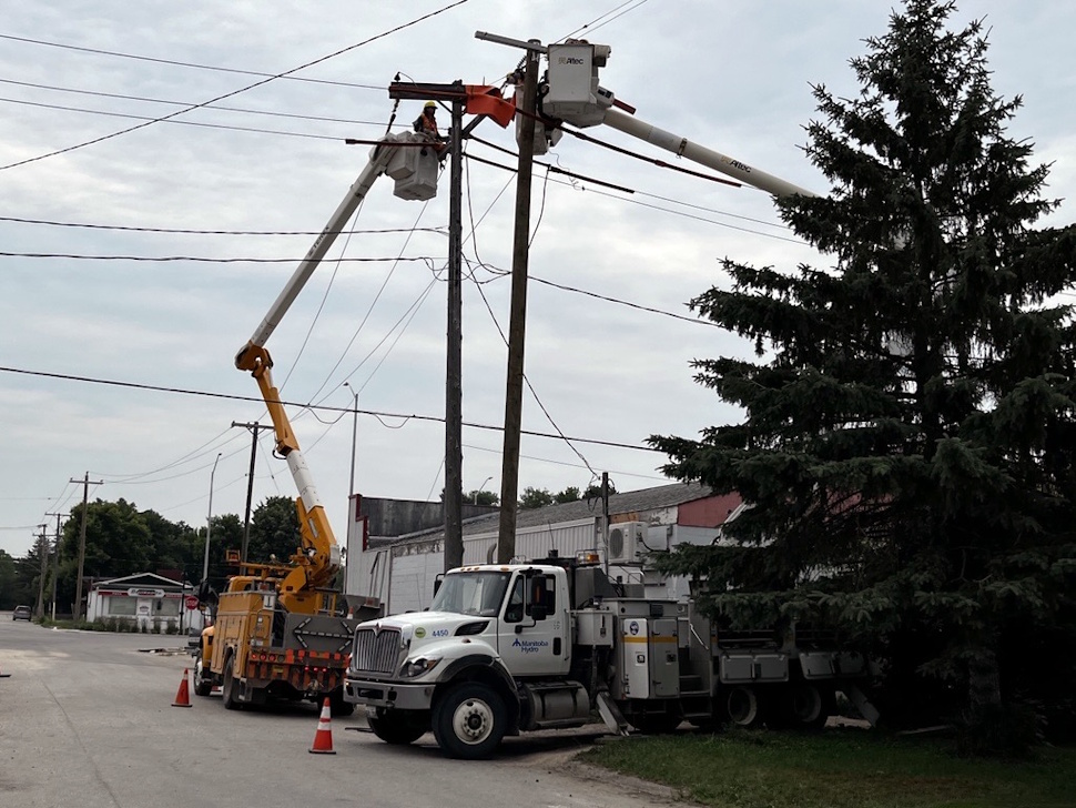 Manitoba Hydro workers repairing a power pole using a bucket truck in Portage la Prairie.