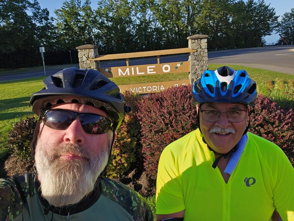 Two men taking a picture wearing bike helmets