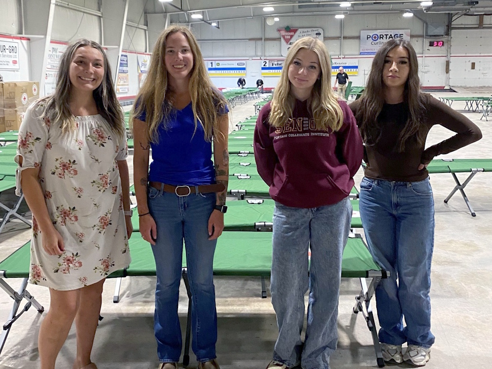 Girls helping set up cots at the Portage Curling Club rink for wildfire evacuees, assisted by PCRC staff and summer students.