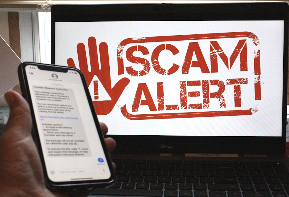 SCAM ALERT on a computer screen and a hand holding a cell phone