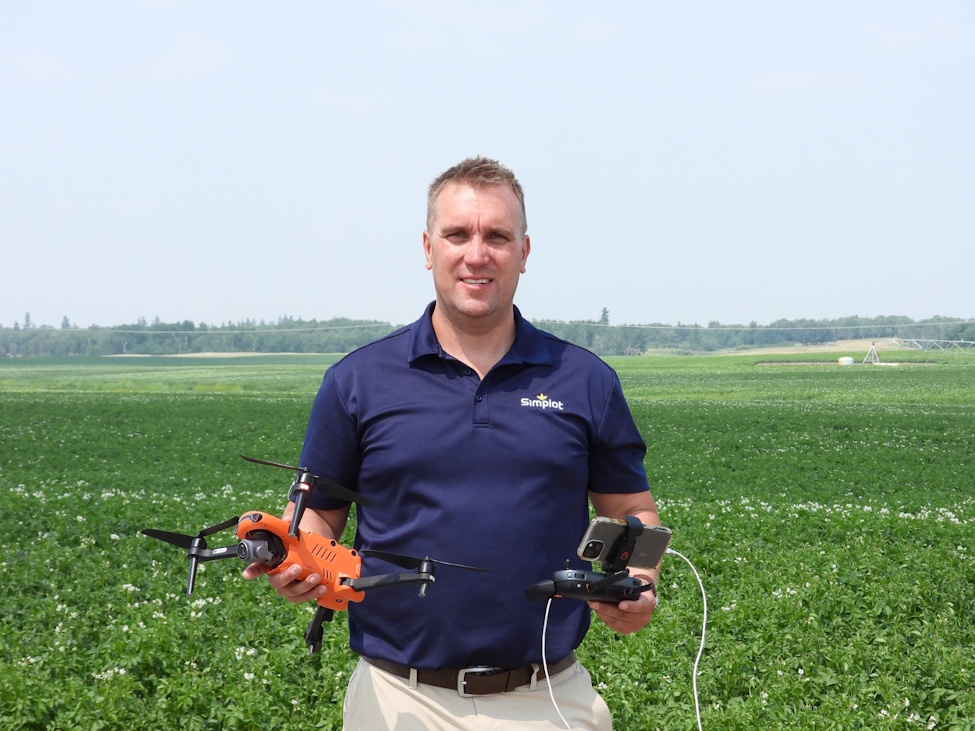a man standing with a drone while in the middle of a field