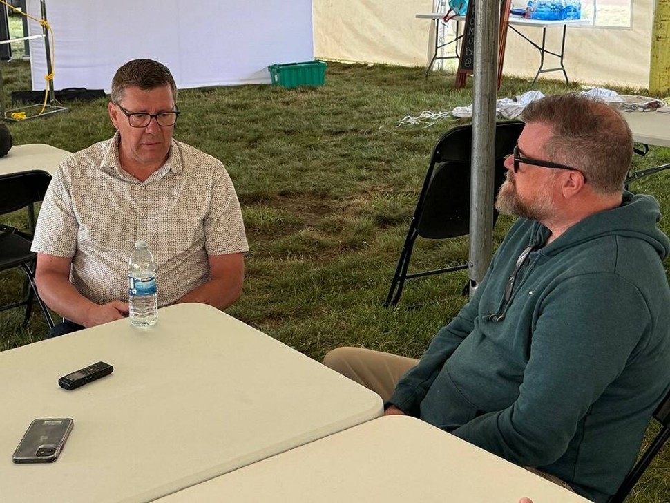 SScott Moe, sits at a table talking with Western Producer reporter Sean Pratt at the Ag in Motion farm show