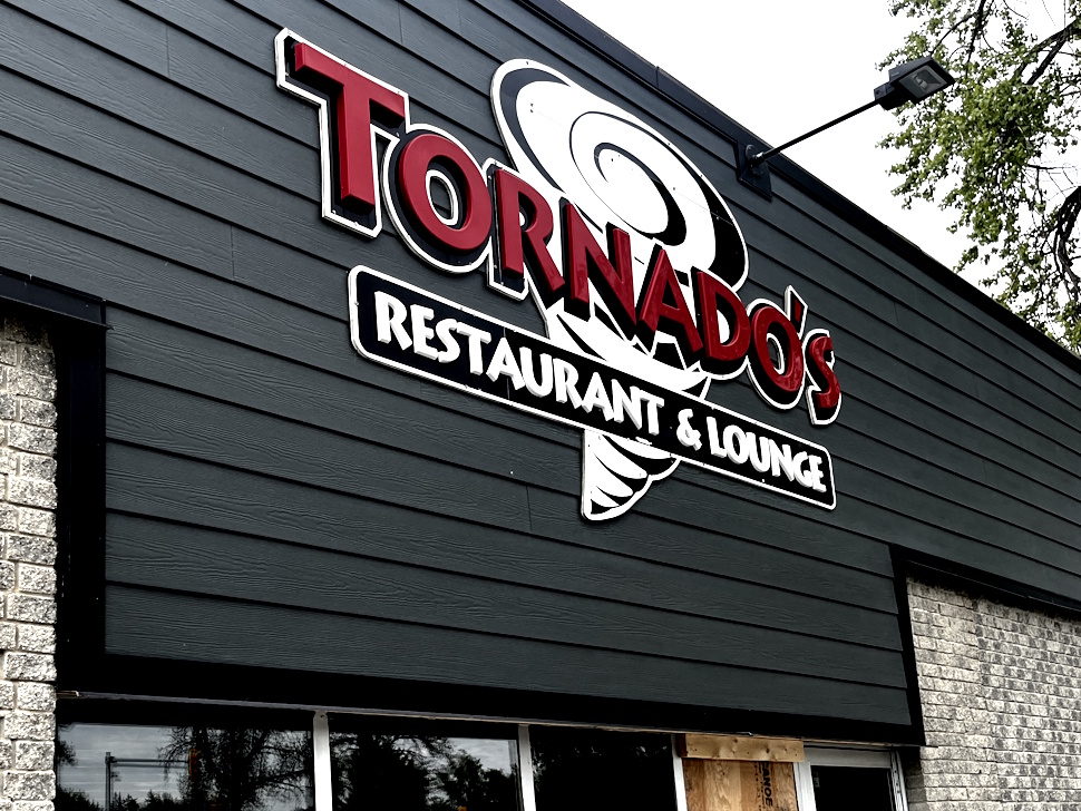 Exterior view of a restaurant with a sign reading “Restaurant and Lounge” on a sunny day.