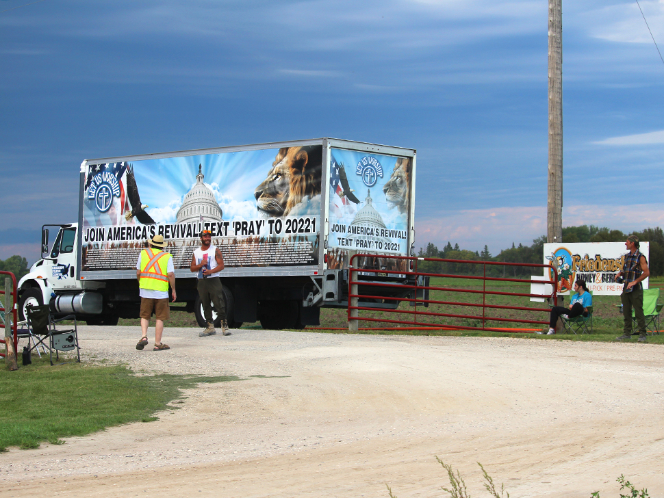 a box truck that reads "Join Americas Revival" next to a sign that reads "Friedensfeld Honey and Berry Farm"
