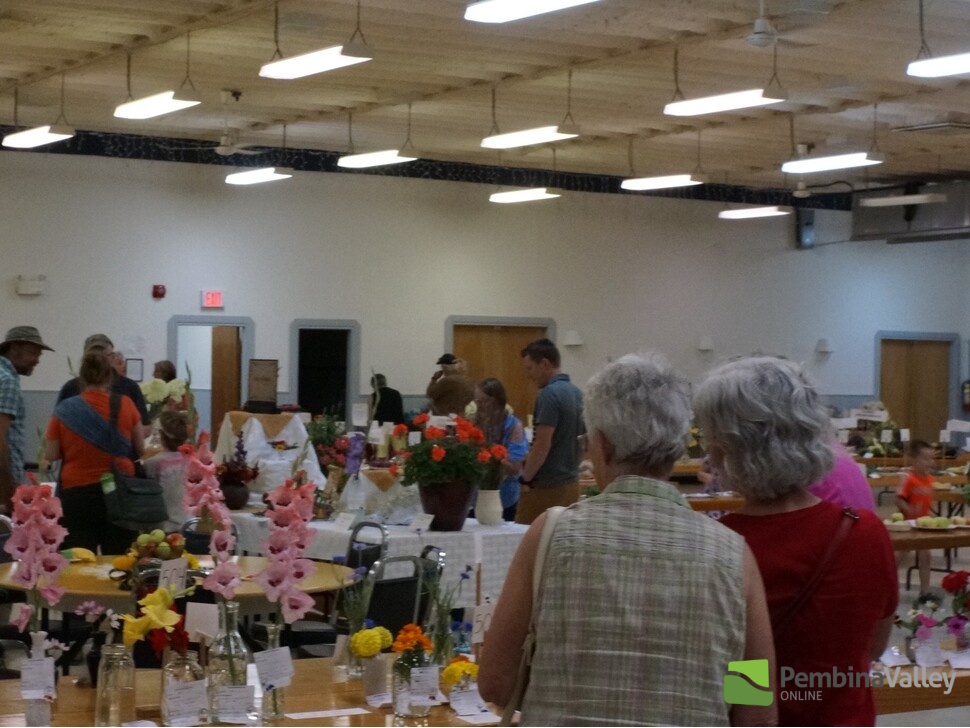 a group of people in a large room with flower arrangements on tables