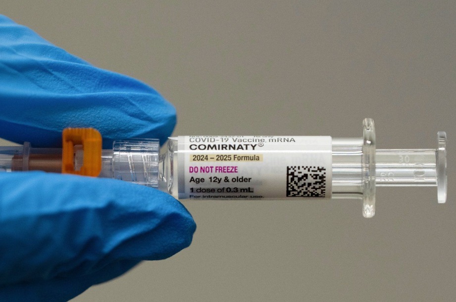 A pharmacist holds a Pfizer and BioNTech COVID-19 vaccine shot on Thursday, April 24, 2025, in Portland, Ore. (AP Photo/Jenny Kane, File)