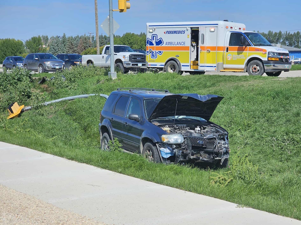 SUV rests in a ditch at the intersection of Saskatchewan Avenue West and Shindleman Way, with traffic lights knocked over and emergency crews on scene.