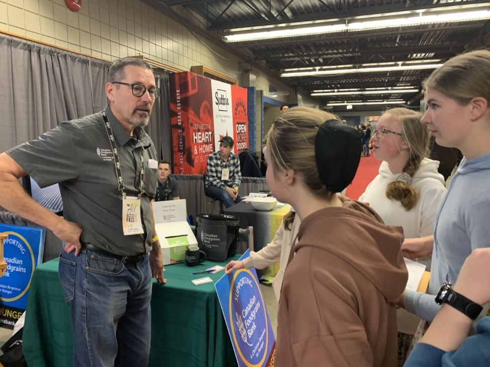 A man is speaking with students at a trade show