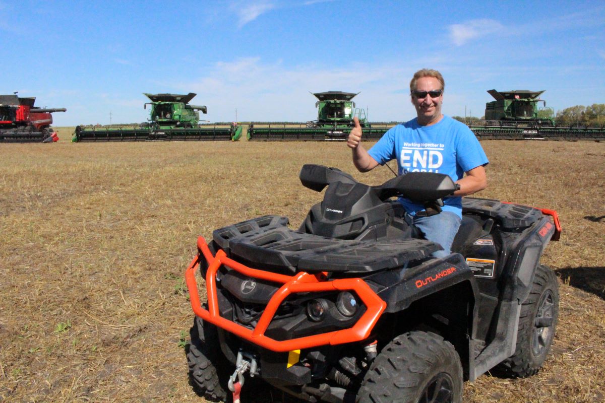 a man on a quad with combines in the background