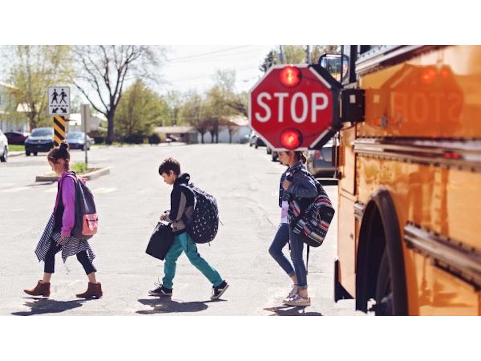 students walking across a road leaving the school bus