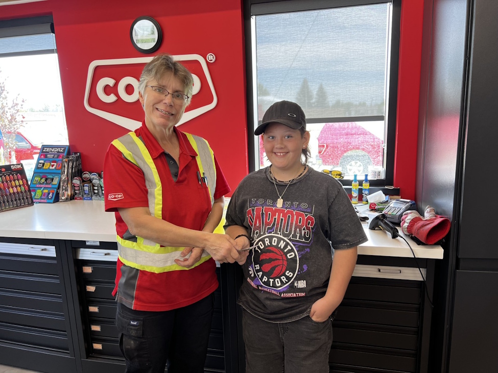 a boy shakes hands with a woman who is the manager of a Co-op gas bar