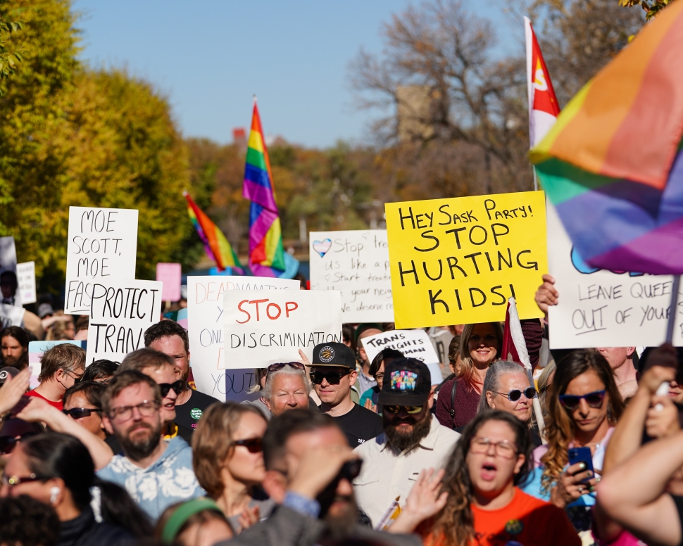 People hold signs while attending a rally against the Saskatchewan government's proposed legislation on pronoun policy in front of the Saskatchewan legislature in Regina, on Tuesday, Oct. 10, 2023. THE CANADIAN PRESS/Heywood Yu
