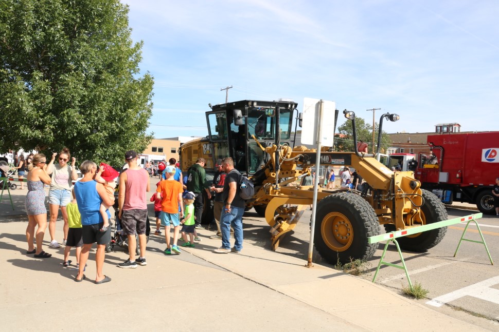 Children line up to hop into the cab of a City of Moose Jaw grader during 2024's Touch-a-Truck event (photo by Cameron Koch)