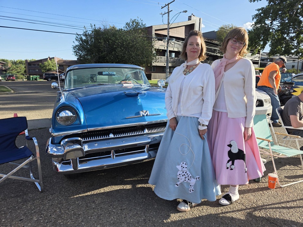 A pair of ladies in classic 1950s outfits stand infront of their ride at Cruisin the Dub. (photos by Hayden Michaels)
