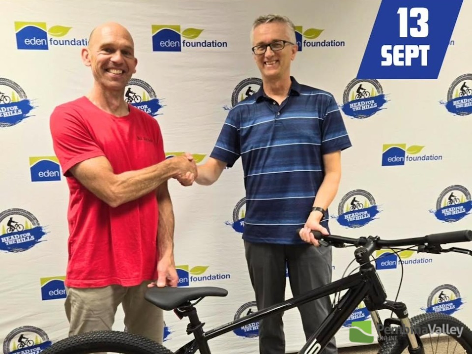 two men shake hands with a bike between them