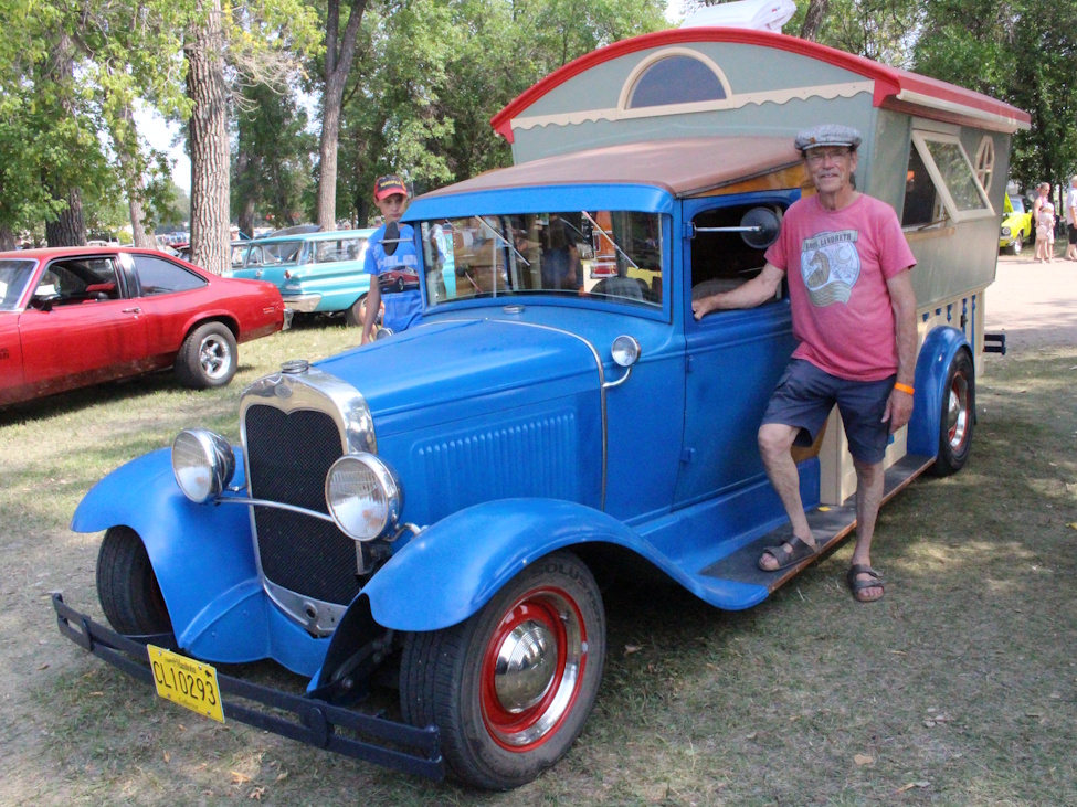 A man standing near his Model A camper truck