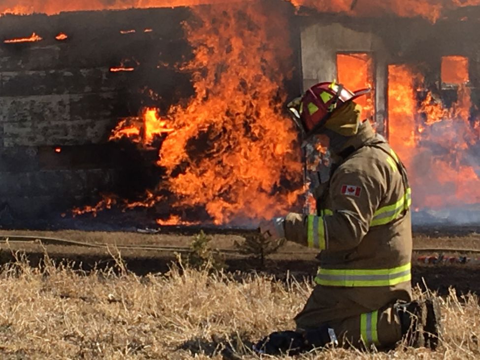 a fireman knelling down in front of a blazing building