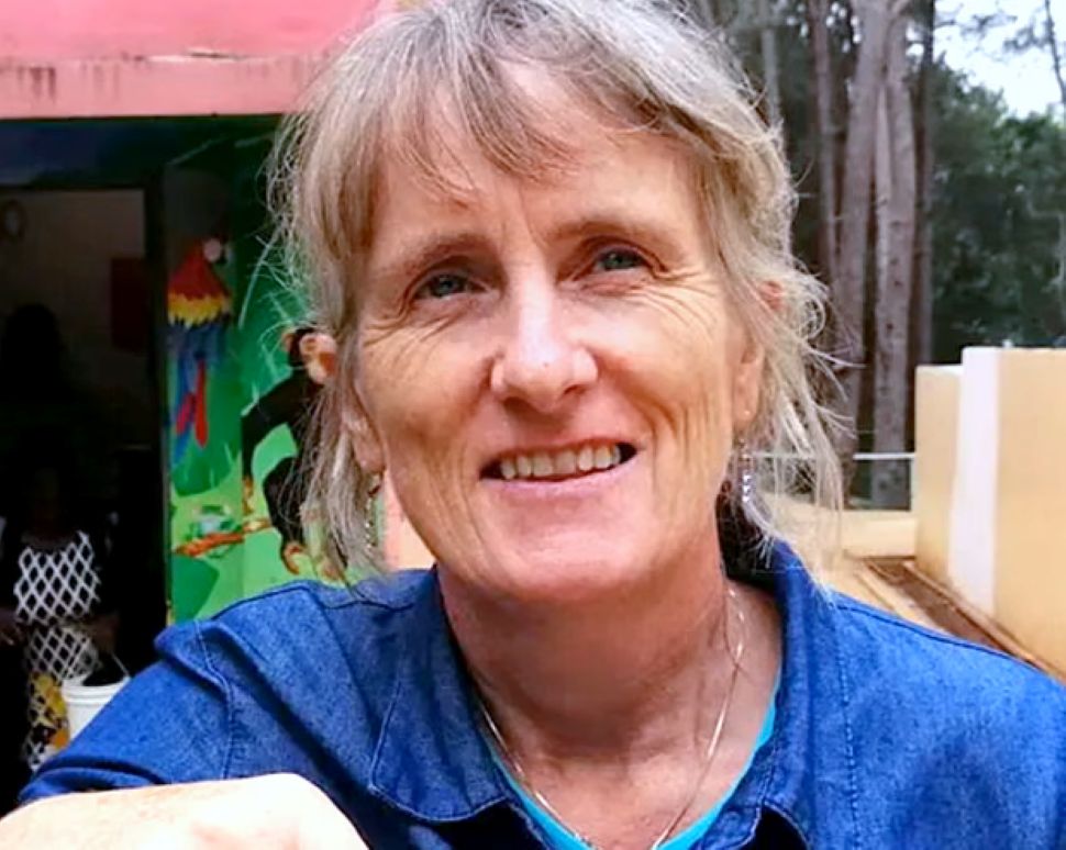 A woman with grey hair sits outside 