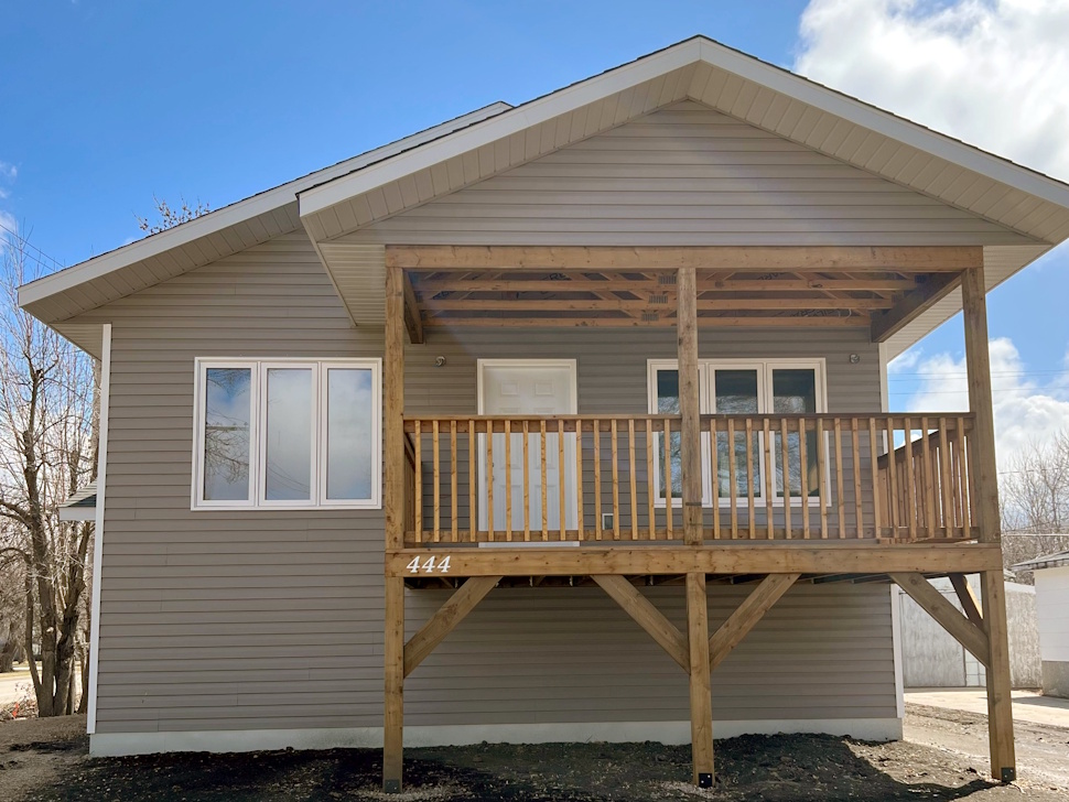 A recently built Habitat for Humanity home in Portage la Prairie, featuring a modest single-family design with a front porch and fresh landscaping.