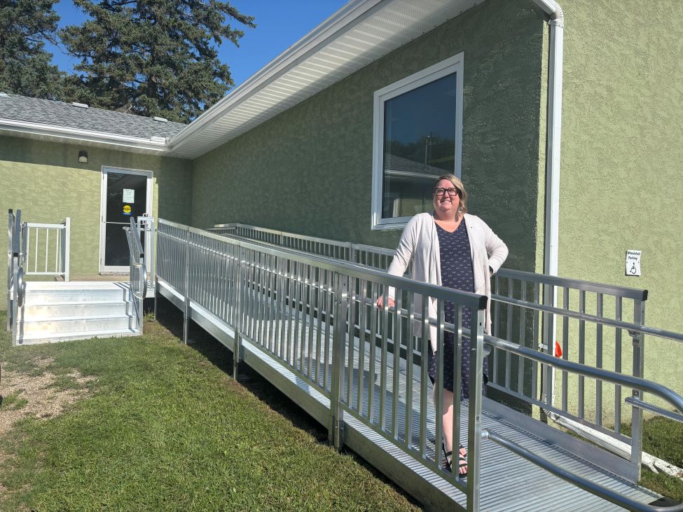 a woman stands on a new wheelchair ramp leading up to a door of a building