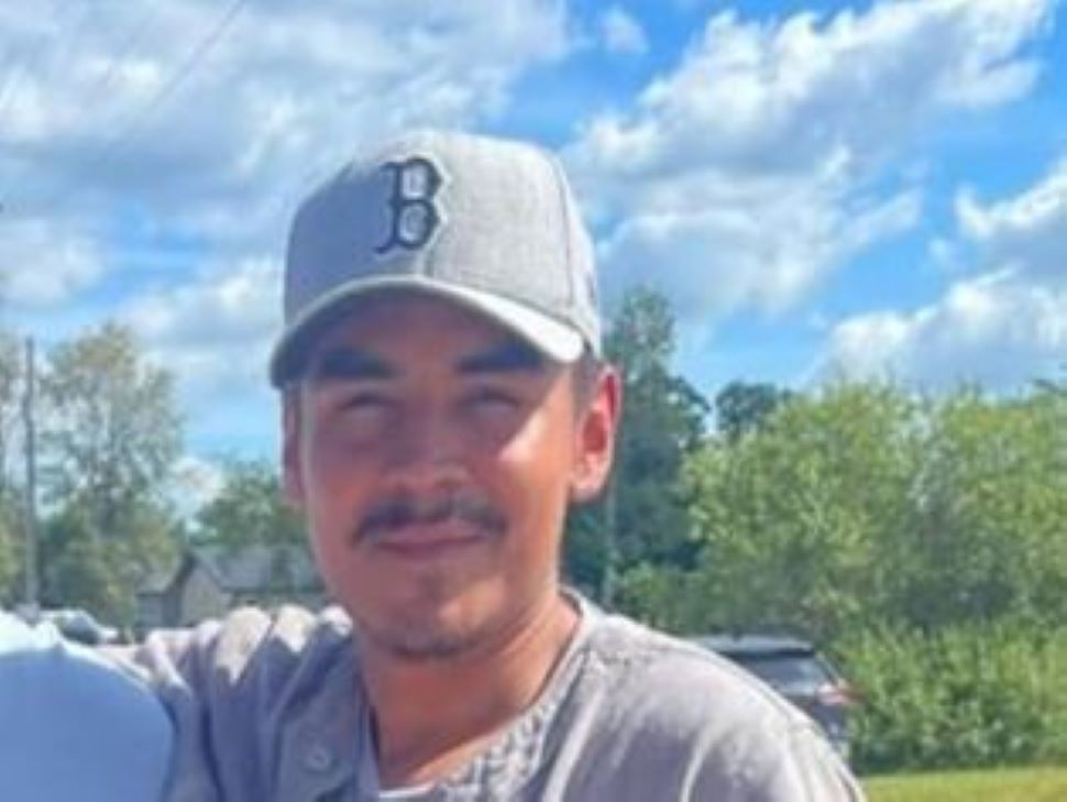 A closeup of a young man standing outside and posing for a photo