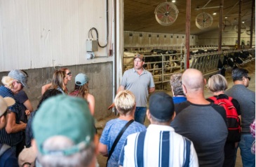 People gathered around listening to a presenter at the Neinhuis Dairy Barn