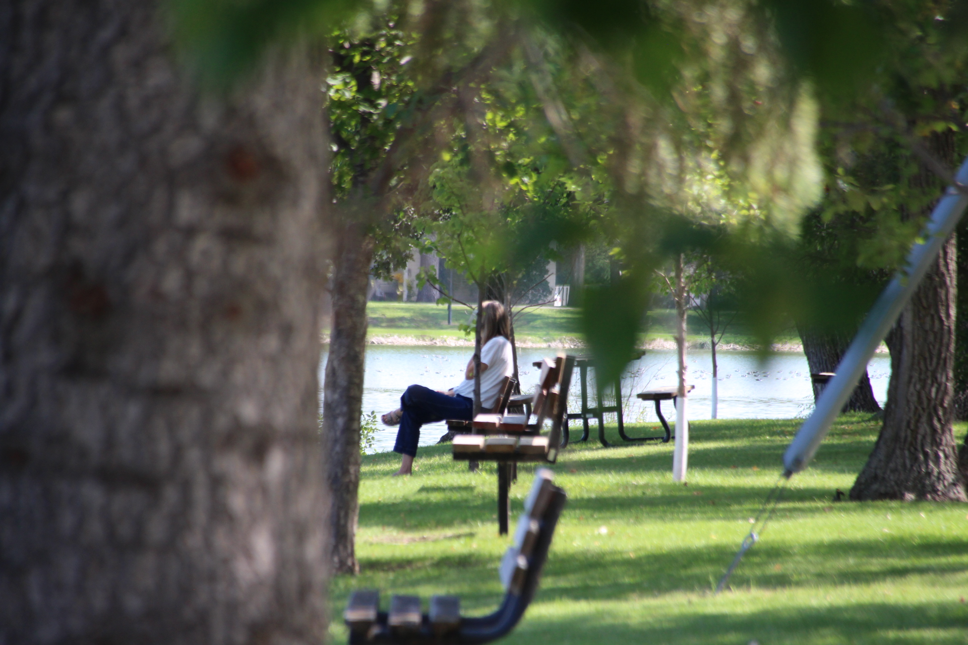 A patron of Island Park enjoying the weather on a park bench near Crescent Lake