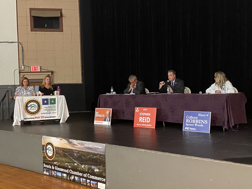 three people behind a table during a debate on stage