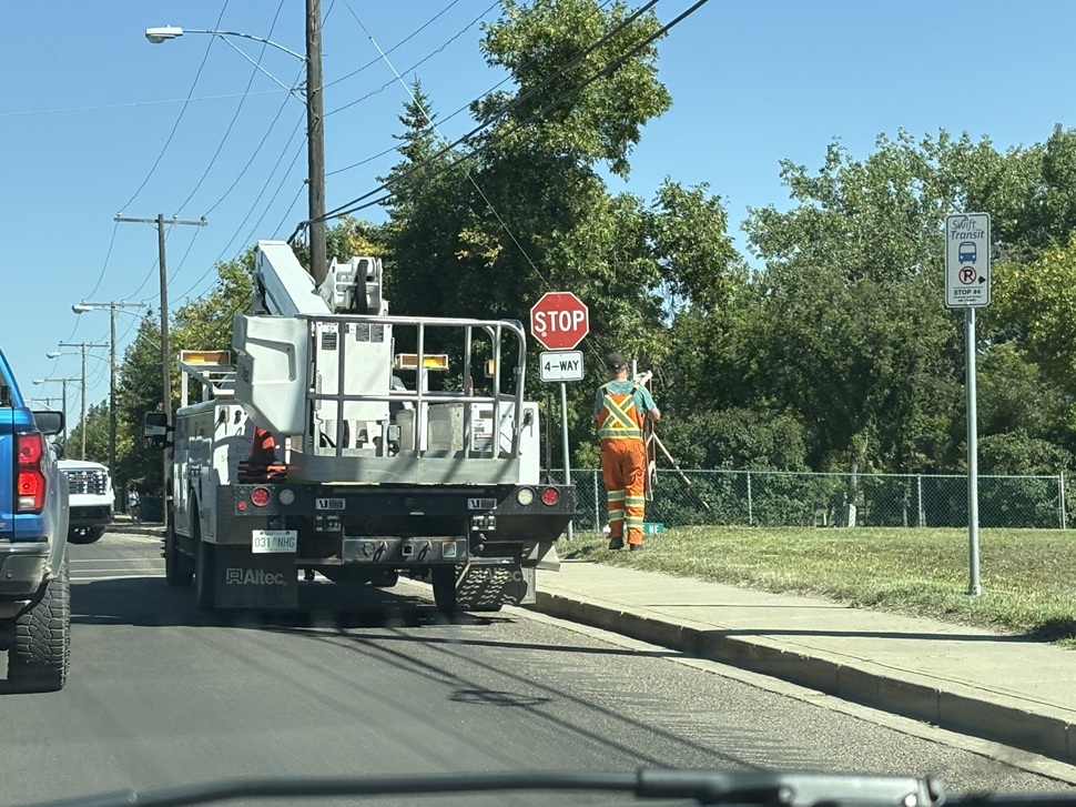 A city worker finishes replacing the last of the stop signs at the intersection of 6th Street NW and Lorne Street West. (photo by Kirsty Hanson)